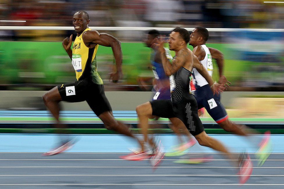 Jamaikalı sprinter Usain Bolt, Rio'daki olimpiyat oyunlarında 100 metre yarı finalini kazanmasına kısa süre kala kameralara gülümsemeyi ihmal etmedi. Finali 9.81 saniyede tamamlayarak birinci olan Bolt, Olimpiyat tarihinde üst üste üçüncü kez 100 metre erkeklerde altın madalya kazanan tek sporcu olarak tarihe geçti.