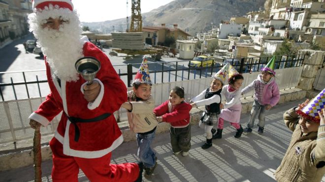 Noel baba kostümlü bir kişi, Şam'ın kuzeyindeki Maalula'da çocuklarla oynuyor