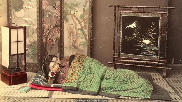 Tipik Japon mobilyalarıyla kaplı bir odada yer yatağında yatan iki Japon kız